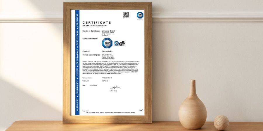 Das HIVAR TÜV und GS Zertifikat für Bürostühle in einem Bilderrahmen auf einer Kommode